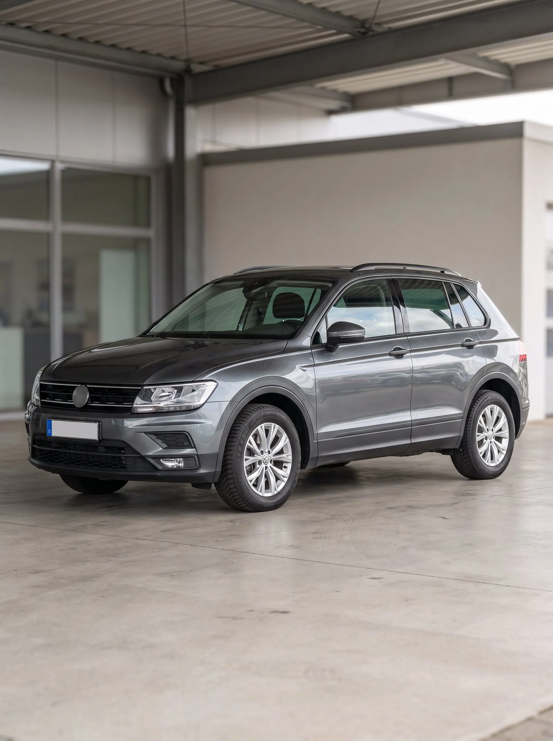 Dunkelgrauer SUV in Dreiviertelansicht unter einem offenen Vordach